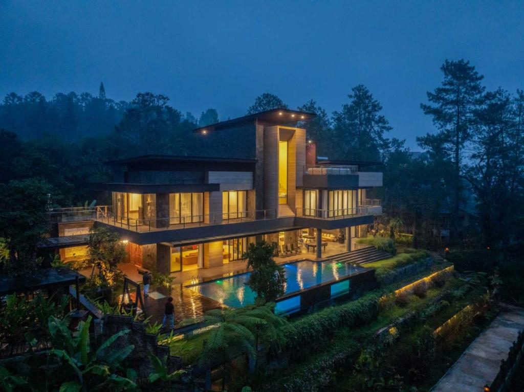 ein großes Haus mit einem davorliegenden Swimmingpool in der Unterkunft Intragama Villa in Puncak
