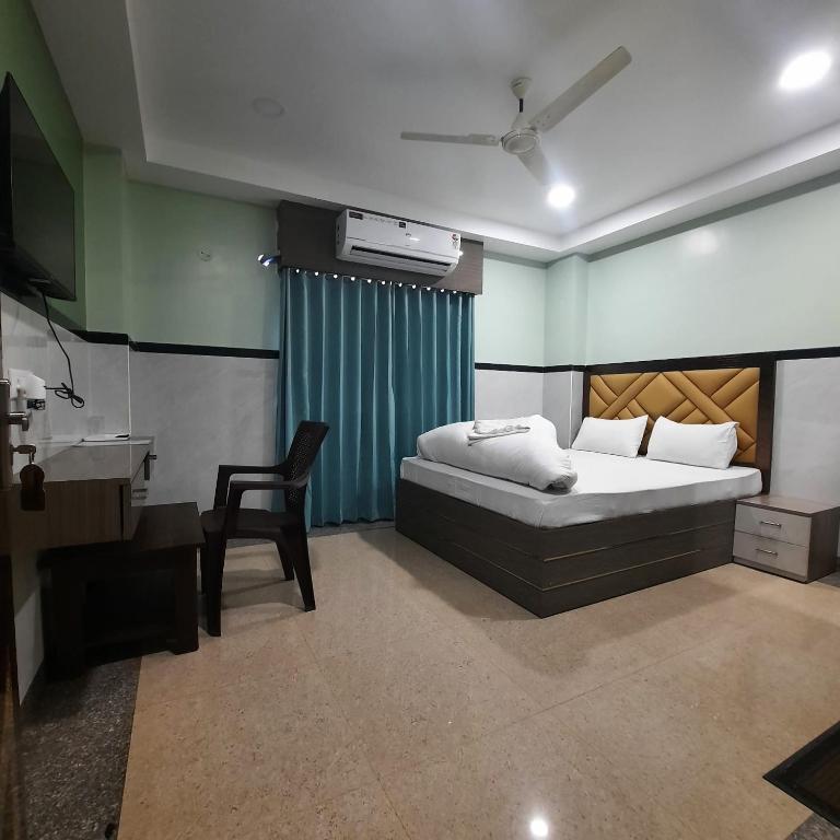 a bedroom with a bed and a chair in it at Surakha INN LLP in Siliguri