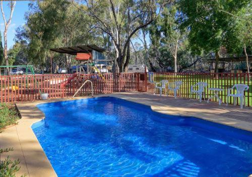 a blue swimming pool with chairs and a fence at BIG4 Barham Holiday Park in Barham
