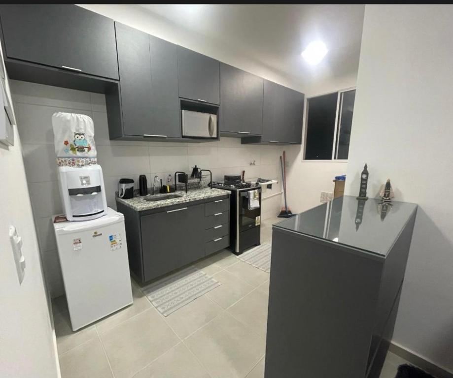a kitchen with black cabinets and a white refrigerator at Doce lar in Pouso Alegre