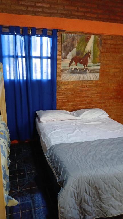 a bedroom with a bed and a blue curtain at Cabañas Arelí in Santa María