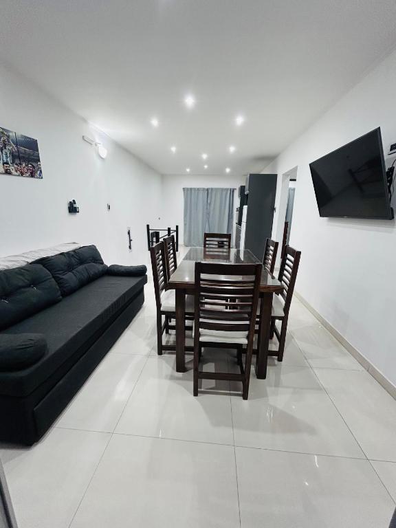 a living room with a couch and a table and chairs at Departamento ESTRADA ideal para pasajeros en tránsito, viajes laborales o estadías cortas Ubicado en Ezeiza, a solo 20 minutos del Aeropuerto Internacional Ministro Pistarini, ofrece comodidad y practicidad para hasta 4 personas in Tristán Suárez