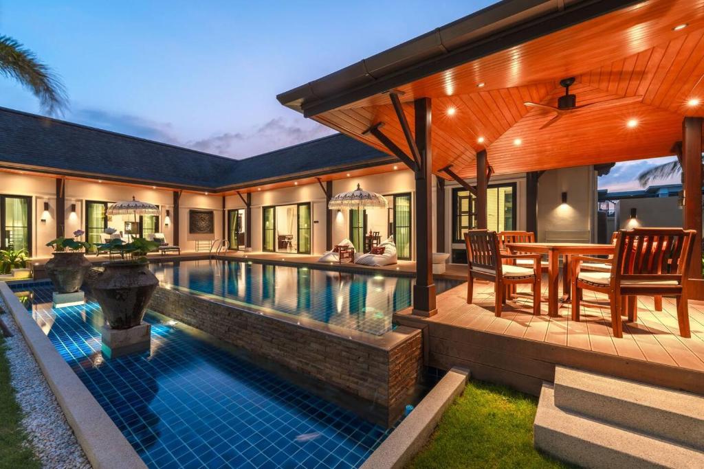 a swimming pool in a house with a table and chairs at Tranquil 4BR Garden Pool Oasis - Layan Beach in Laguna Phuket