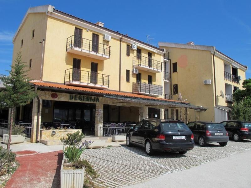 a large building with cars parked in a parking lot at Apartments and Rooms Degenija in Starigrad-Paklenica