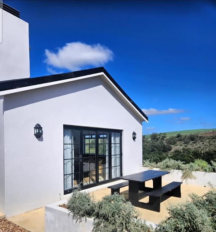 a white house with a picnic table in front of it at Podium Farm Stay in Swellendam