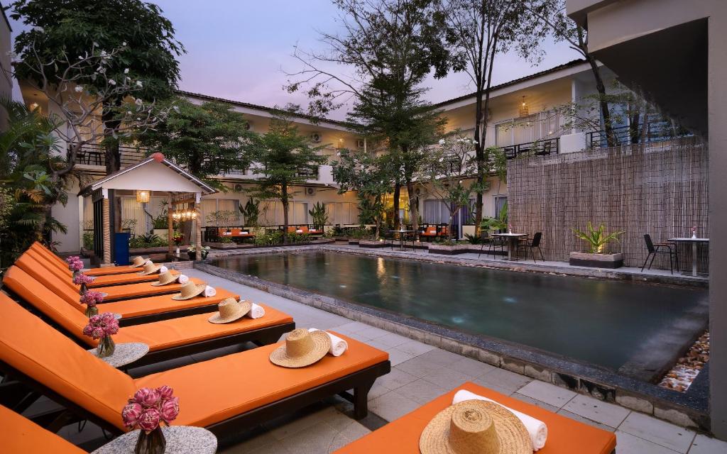 a hotel with a swimming pool and tables with hats on them at Indochine Sanctuary Hotel in Siem Reap