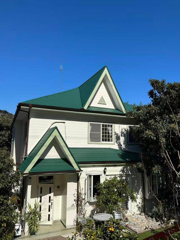 a white house with a green roof at 枇杷物語 in Shimo-taga