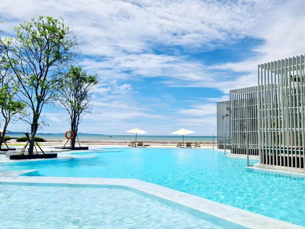 a large swimming pool next to a beach at 2BR Family Condo - Veranda Pattaya - Beachfront in Na Jomtien