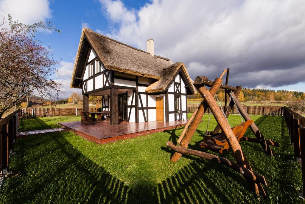une petite maison avec un toit de chaume sur un champ verdoyant dans l'établissement Hereczówka, à Laskówka