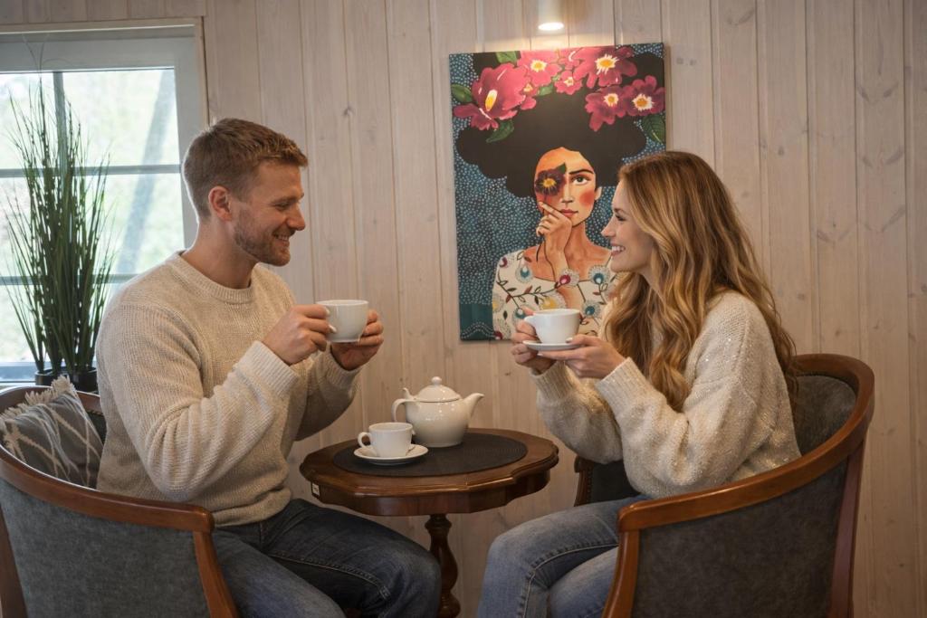 a man and a woman sitting in chairs drinking coffee at Cozy studio in a horse ranch in Lieplaukė