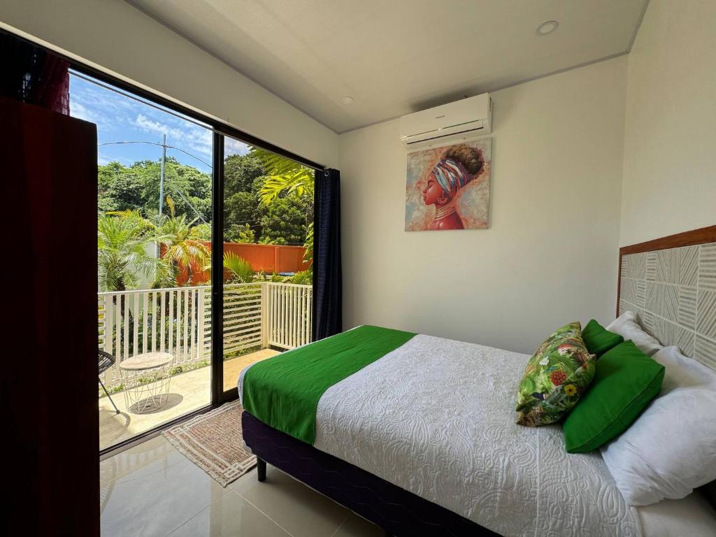 a bedroom with a bed and a large window at Sloth House - Centric 2BR with shared pool in Puerto Viejo