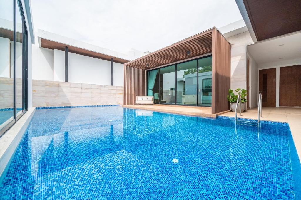 an infinity pool in a house with a building at Movenpick Residences 4-Bedroom Pool Villa Beach Access, Na Jomtien Pattaya in Na Jomtien