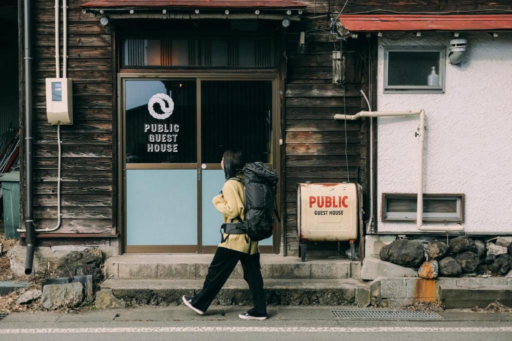 a woman walking down the street in front of a building at Public Guest House in Karuizawa