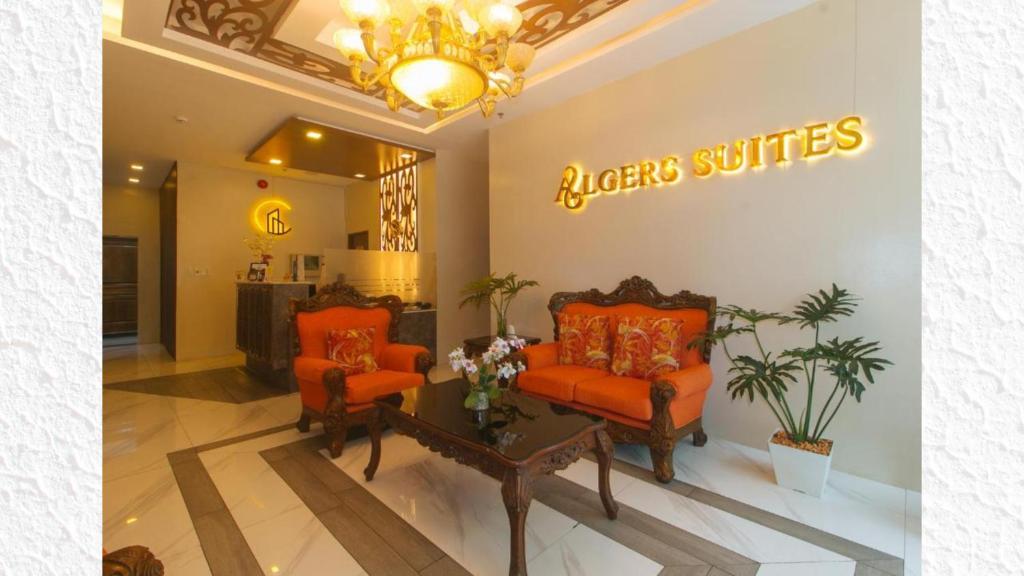 a lobby with two orange chairs and a sign on the wall at Algers Suites in Manila