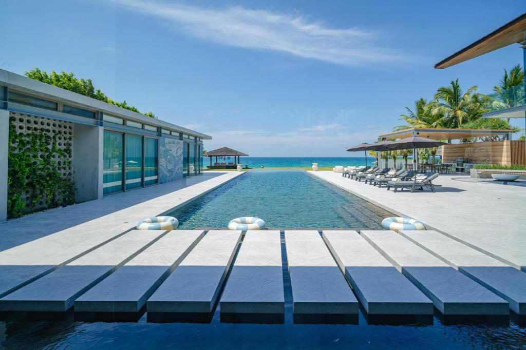 a swimming pool next to a resort with the ocean at Villa Essenza in Ban Han Pa To