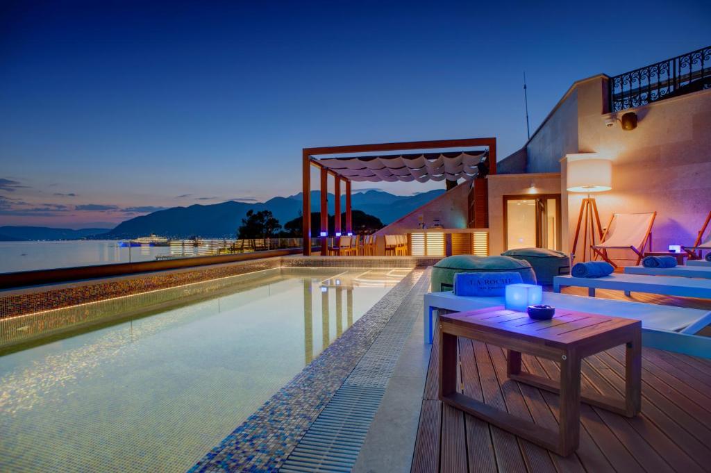 a house with a pool and a table on a deck at Boutique Hotel La Roche in Tivat