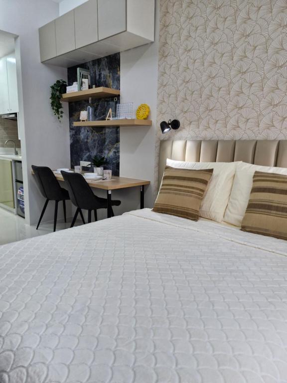 a bedroom with a large white bed and a table at WeStay by KM Staycations in Dagupan