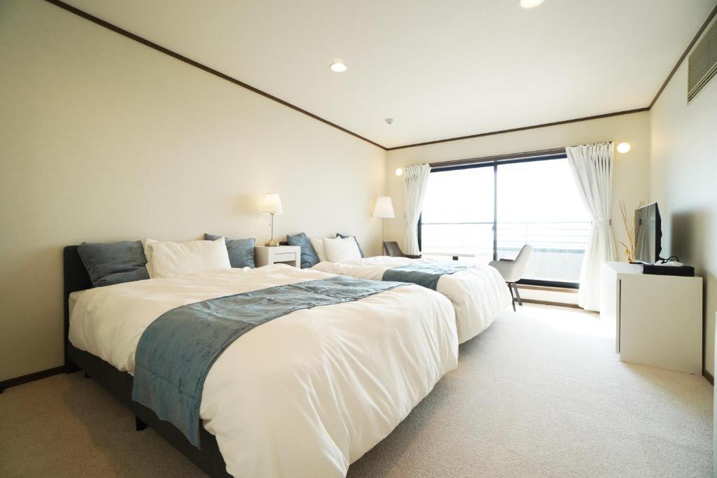 a bedroom with two beds and a large window at Suma Beach House Ref in Takatorichō