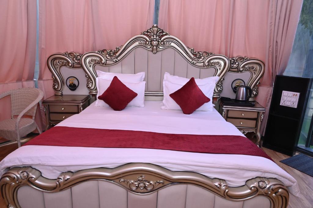 a bedroom with a large bed with red pillows at Prakriti Hill Resort in Nandaprayāg