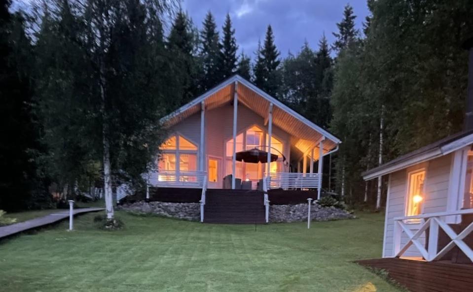 a large house with lights on in the yard at Genuine Beach House and Sauna in Pello