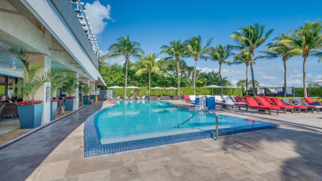 uma piscina num resort com cadeiras e palmeiras em Miami Beachfront Bentley Hotel Studio Condo with Balcony em Miami Beach