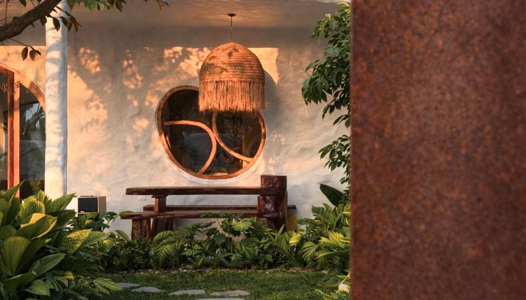 a wooden bench with a round mirror on a wall at AnB Garden in Ða Gia