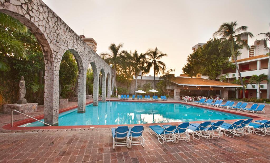 uma grande piscina com cadeiras e um edifício em El Cid Granada Hotel & Country Club em Mazatlán