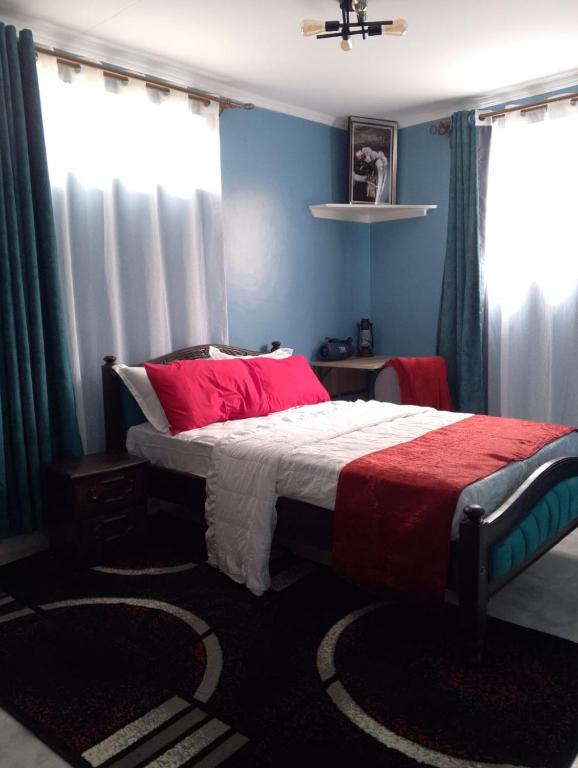a bedroom with a bed with a red and white blanket at SQ Acacia in Langata Rongai