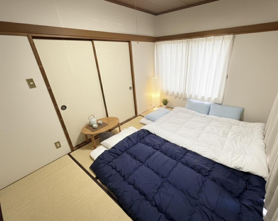 a bedroom with a large bed with a blue blanket at RHK Guest House102 in Tokyo