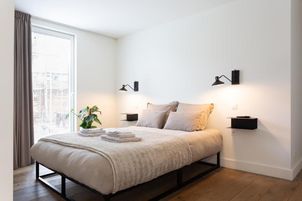 a white bedroom with a bed and a window at De Wilden Ezel in Mol