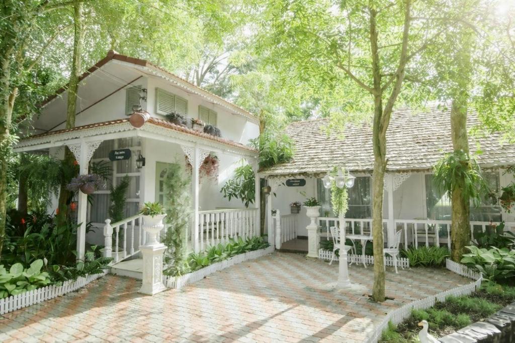 a white house with a white fence and trees at Our Time Staycation in Ban Chak Makham
