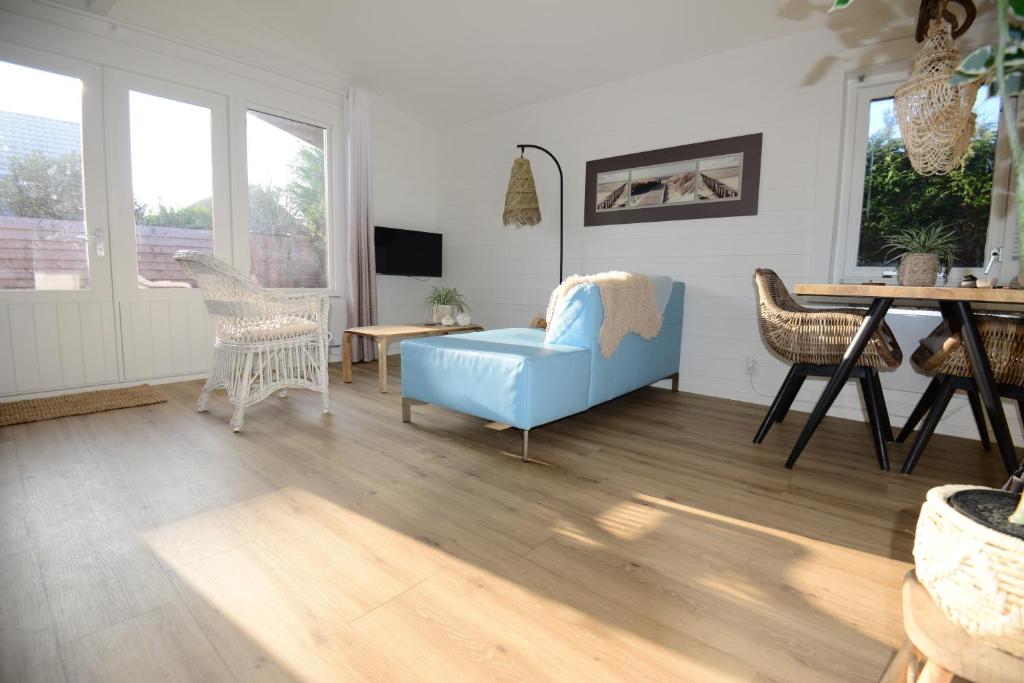 a living room with a blue couch and a table at Tussen duin en dijk in Warmenhuizen