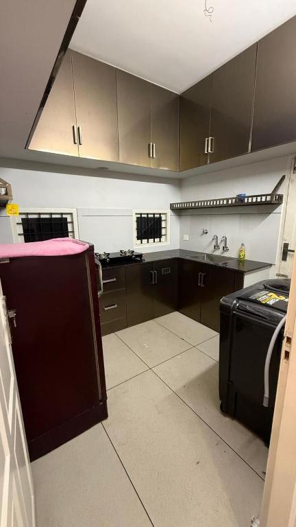 a kitchen with brown cabinets and a black stove at sahara private villa in Cochin