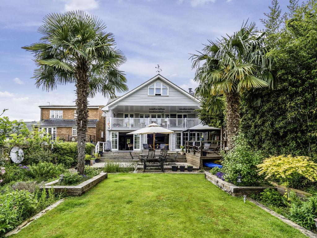 a house with two palm trees in the yard at River Haven - River Thames frontage house in Thames Ditton
