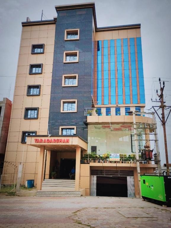 a tall building with windows and a balcony at Hotel Tara Darshan in Tarapith