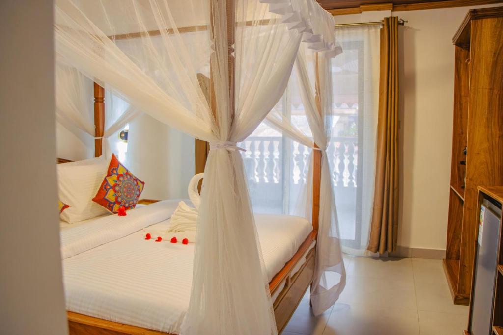 a bedroom with a white canopy bed with a window at Shangani Hotel in Zanzibar City