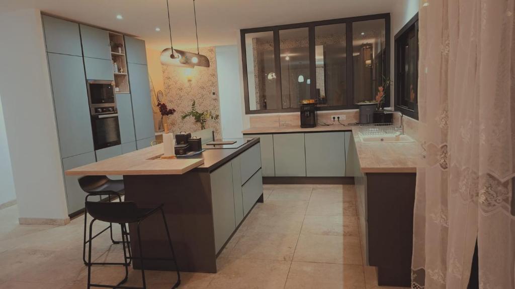 Una cocina con una isla con encimera y taburetes. en Chez moi, en Gan