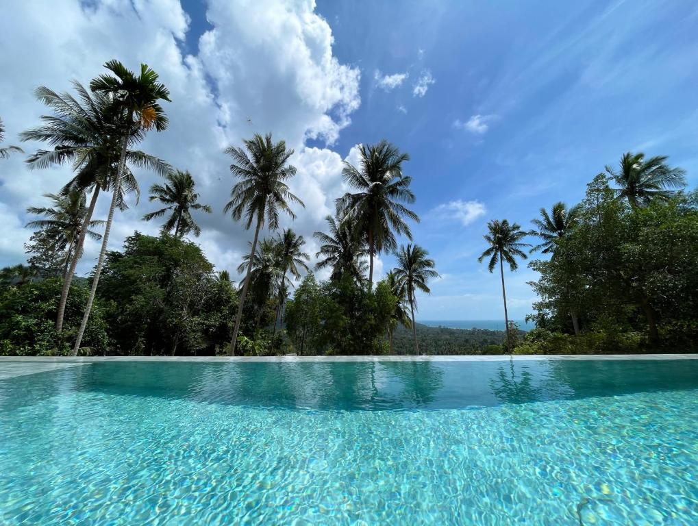 a swimming pool with palm trees in the background at Altura Villa Pool & Panoramic View in Ban Nong Chaeng