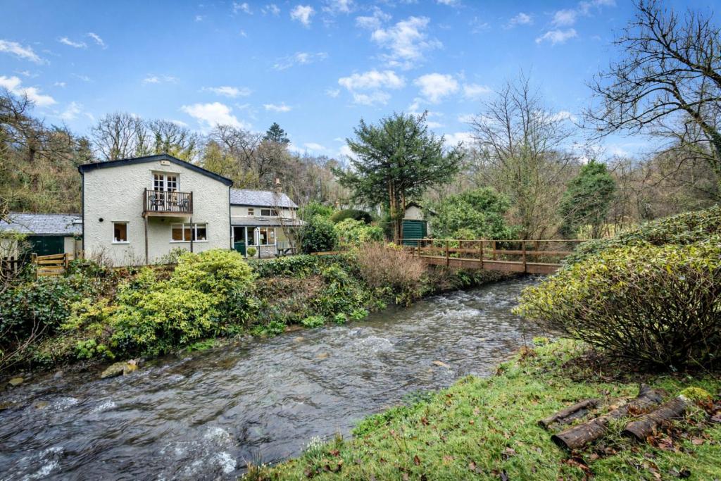 a house next to a river next to a house at Finest Retreats - Dolhyfryd Lodge in Denbigh