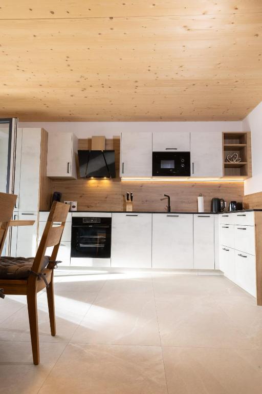 a kitchen with white cabinets and a wooden ceiling at Huawa Appartements in Öblarn