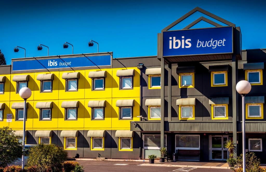 a yellow building with a sign for its hotel at ibis Budget - Fawkner in Melbourne