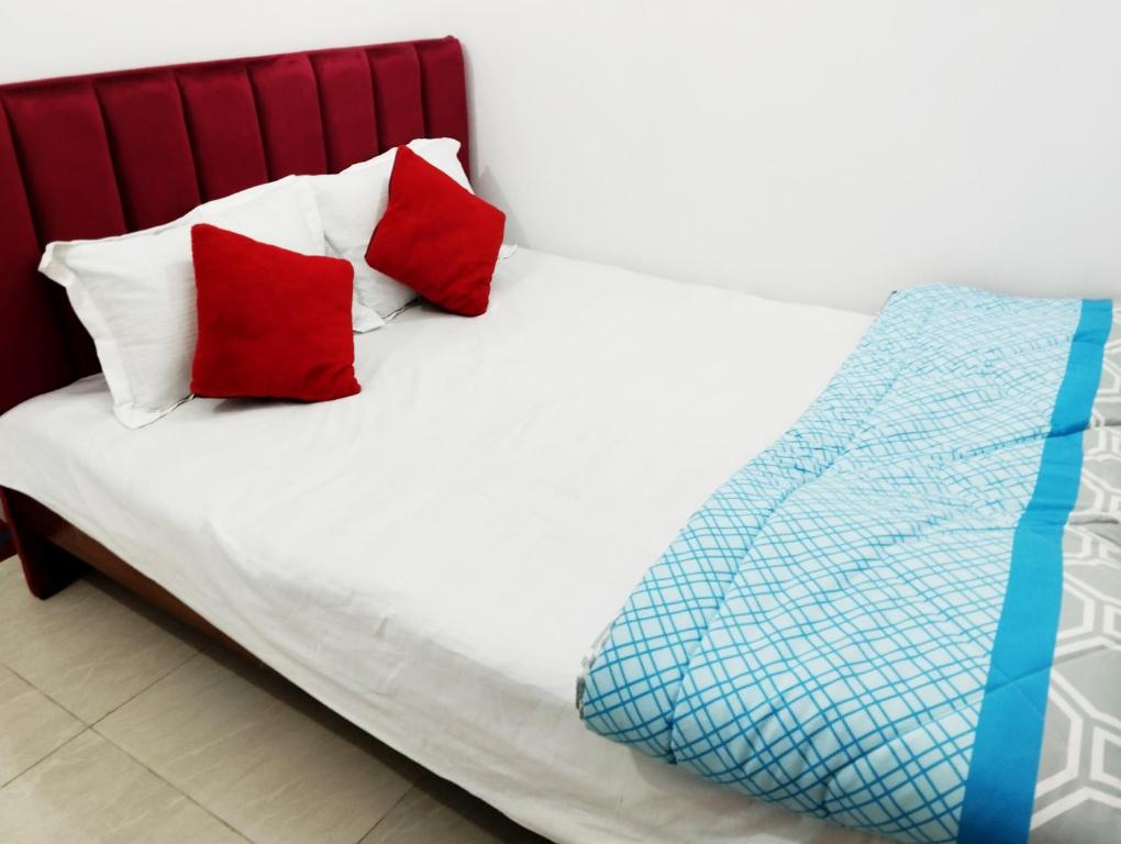 a bed with two red pillows on it at Hotel Dhanmondi Prime in Dhaka
