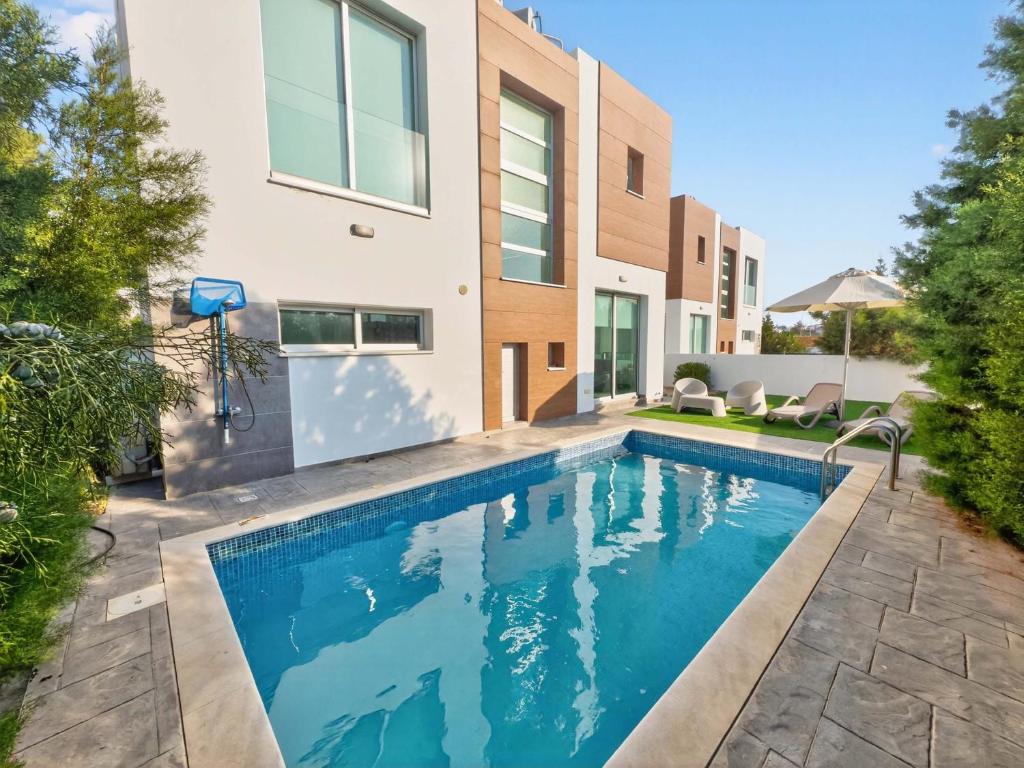 a swimming pool in front of a house at Alassia Blue Villa in Protaras