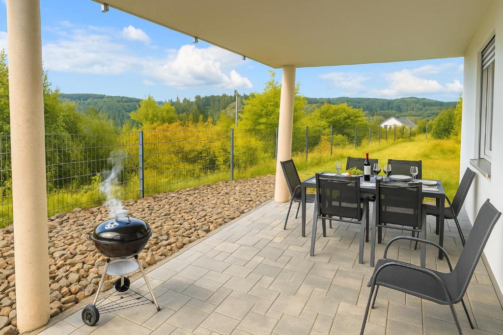 a patio with a grill and a table and chairs at Ferienwohnung Abbey in Müllensiefen