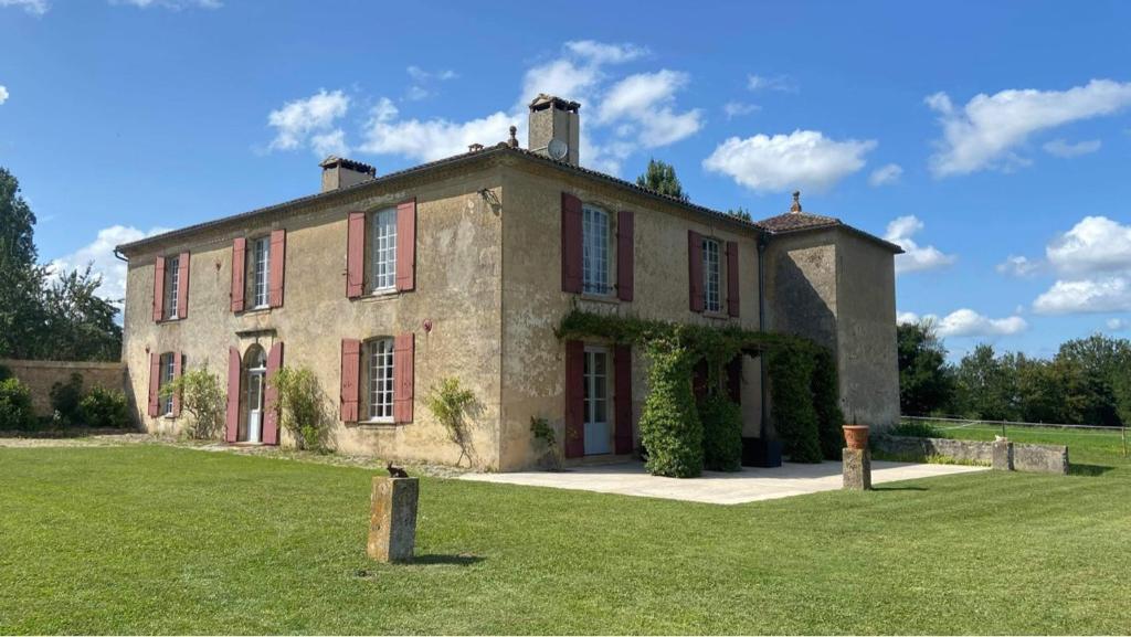 a large brick house with a grass field in front at Beaulieu Saint Come in Saint-Côme