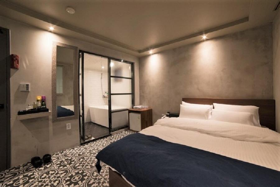 a bedroom with a bed and a bathroom with a tub at MW Hotel in Seoul