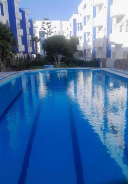 a large blue swimming pool with buildings in the background at Suite Home martil in Martil