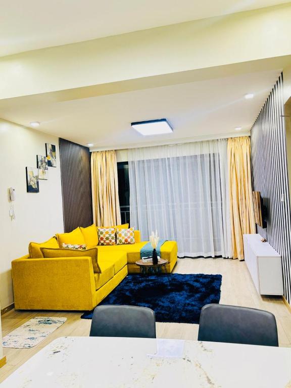 a living room with a yellow couch and a table at Urban Stays-Two bedroom Near JKIA Airport in Nairobi