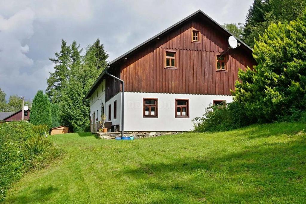 a large red and white barn on a grassy hill at Chalupa U Kapličky Pastviny in Pastviny