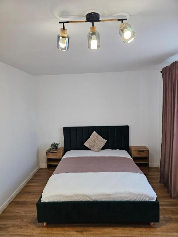 a bedroom with a bed with a black headboard and lights at At Ladyluck in Suceava